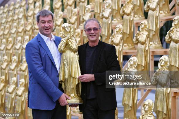 The concept artist Ottmar Hoerl and the Bavarian minister of homeland affairs Markus Soeder stand between golden Madonna figurines in Nuremberg,...