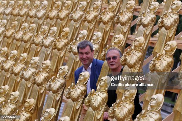 The concept artist Ottmar Hoerl and the Bavarian minister of homeland affairs Markus Soeder stand between golden Madonna figurines in Nuremberg,...