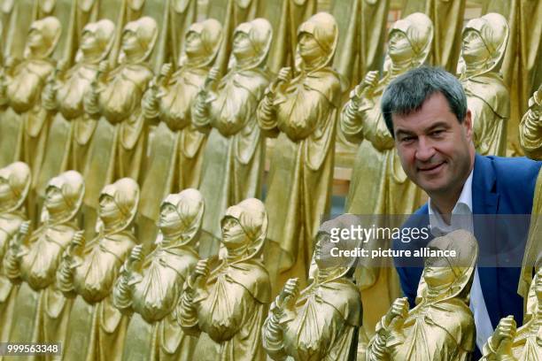 The Bavarian minister of homeland affairs Markus Soeder stands between golden Madonna figurines in Nuremberg, Germany, 1 September 2017. Hoerl's art...