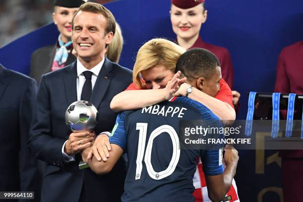 French President Emmanuel Macron and Croatian President Kolinda Grabar-Kitarovic congratulate France's forward Kylian Mbappe during the trophy...