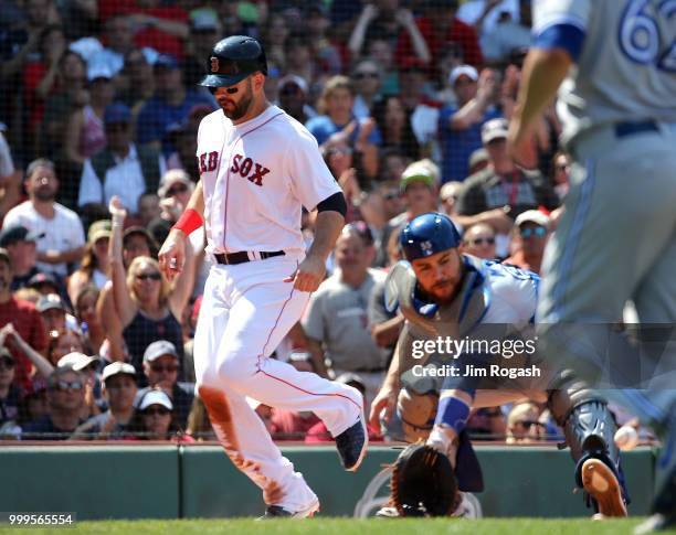 Mitch Moreland of the Boston Red Sox scores a run as Russell Martin of the Toronto Blue Jays fields a late throw in the sixth inning at Fenway Park...