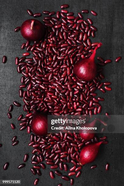 red beans and onion scattered on the black table - alina stockfoto's en -beelden