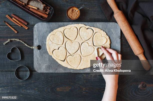 female hands cut the cookies-hearts from the dough - alina stockfoto's en -beelden