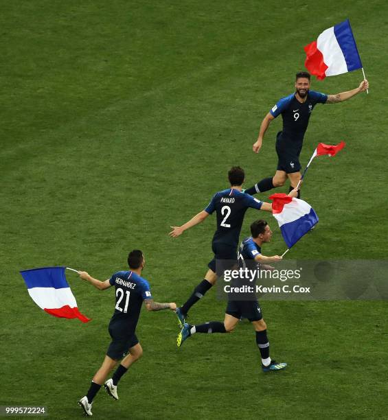 Olivier Giroud of France and team mates run with French flags in celebration following the 2018 FIFA World Cup Final between France and Croatia at...