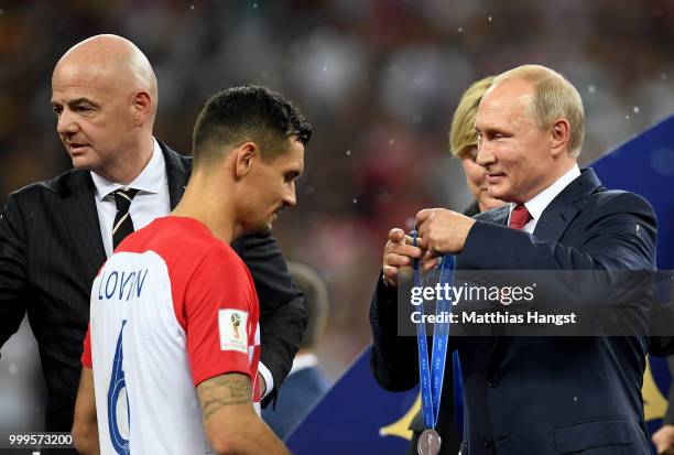 President of Russia Vladimir Putin presents Dejan Lovren of Croatia with his runners up medal following the 2018 FIFA World Cup Final between France...