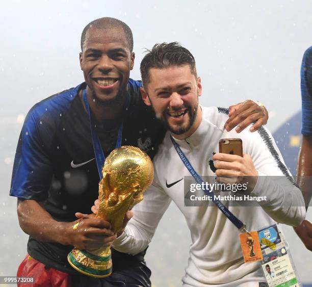 Djibril Sidibe of France and Arnaud Berry celebrate victory with the World Cup trophy during the 2018 FIFA World Cup Final between France and Croatia...