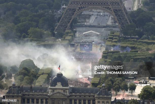 This picture taken from the panoramic observatory of the Montparnasse Tower shows people reacting in the fan zone on the Champs de Mars near the...