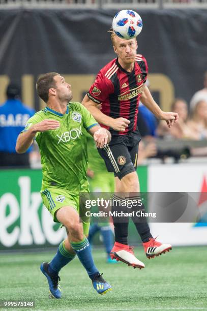 Jeff Larentowicz of Atlanta United heads the ball by Will Bruin of Seattle Sounders FC 2 during the game at Mercedes-Benz Stadium on July 15, 2018 in...