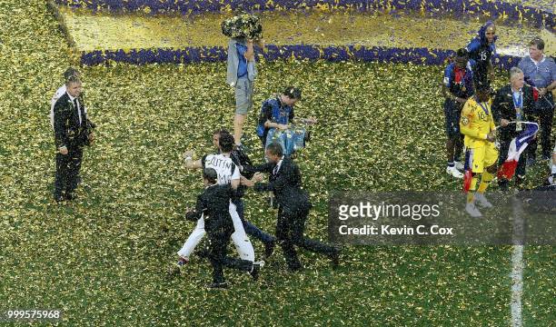 Pitch invaders are removed from the pitch during the World Cup trophy presentation following the 2018 FIFA World Cup Final between France and Croatia...