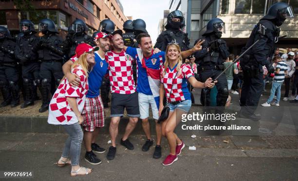 July 2018, Germany, Stuttgart: Soccer: World Cup, France vs Croatia, Final. Croatian fans taking a selfie before a group of police officers in the...