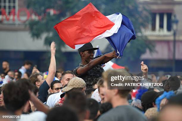 Peopler wave a French national flag as they celebrate after France won the Russia 2018 World Cup final football match between France and Croatia, on...