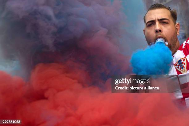 July 2018, Germany, Stuttgart: Soccer: World Cup, France vs Croatia, Final. A Croatian fan holding a firework in his mouth in the Theodor Heuss...