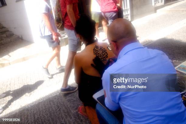 Street artist makes a tattoo to a tourist in Granada, Spain, on July 15, 2018.
