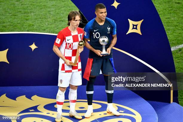 Croatia's midfielder Luka Modric poses with the Golden Ball, next to France's forward Kylian Mbappe, who in turn carries the Best Young Player Award...