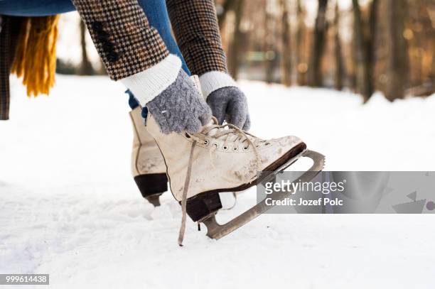 unrecognizable woman in winter clothes putting on old ice skates - jozef polc stock pictures, royalty-free photos & images
