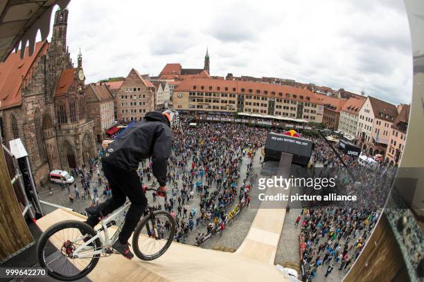 Freestyle mountainbiker on a ramp during training at the "Red Bull District Ride" with the Hauptmarkt in the background, in Nuremberg, Germany, 2...