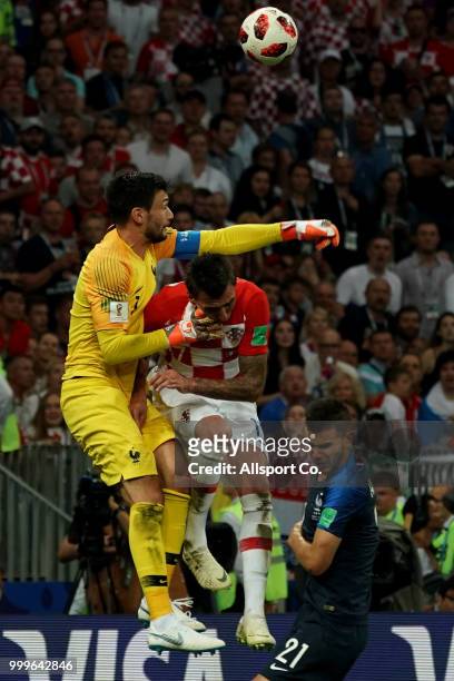 Hugo LLoris of France punches the ball while challenge by Mario Mandzukic during the 2018 FIFA World Cup Russia Final between France and Croatia at...