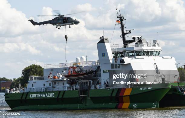 Members of the Zentrale Unterstuetzungsgruppe Zoll lower themselves onto the customs suip "Helgoland" during a demonstration, as part of Tag des...