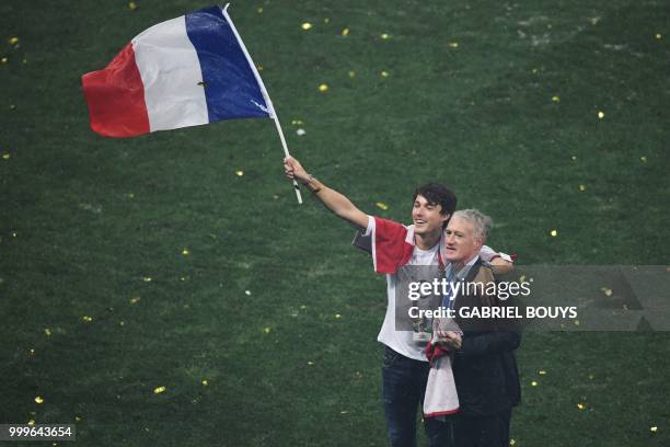 France's coach Didier Deschamps celebrates with his son Dylan Deschamps waving the French national flag during the trophy ceremony after winning the...