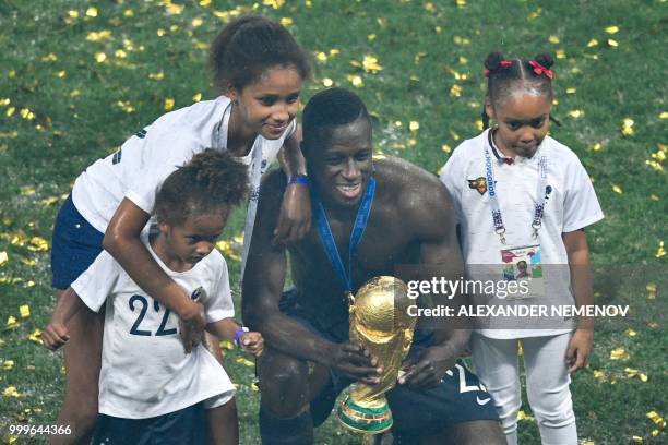 France's defender Benjamin Mendy poses with the trophy and his daugters during the trophy ceremony after winning the Russia 2018 World Cup final...