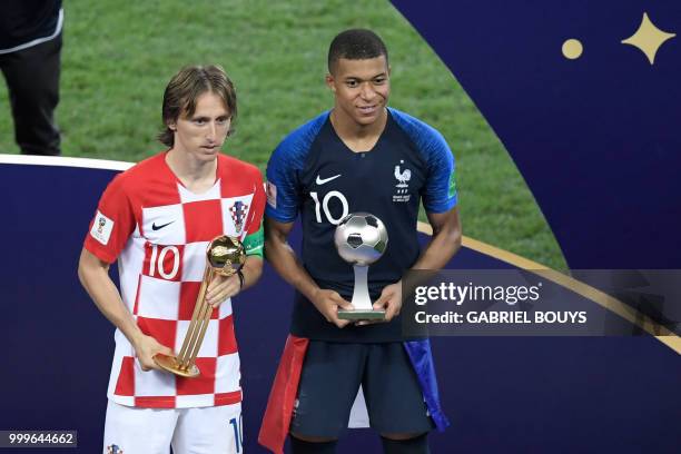 Croatia's midfielder Luka Modric poses with the Golden Ball, next to France's forward Kylian Mbappe, who in turn carries the Best Young Player Award...