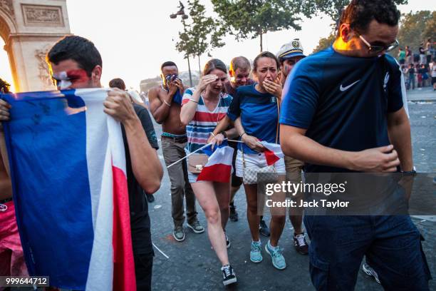 French football fans react to tear gas as they celebrate on the Champs-Elysees after France's victory against Croatia in the World Cup Final on July...