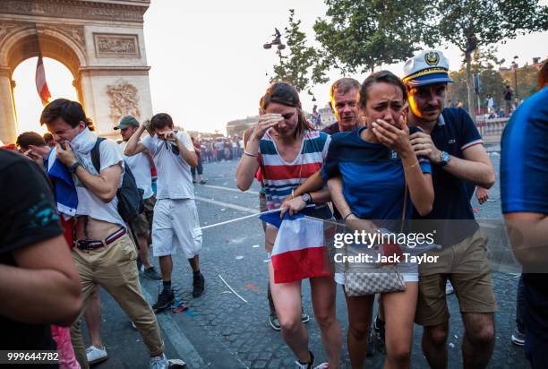 French football fans react to tear gas as they celebrate on the Champs-Elysees after France's victory against Croatia in the World Cup Final on July...