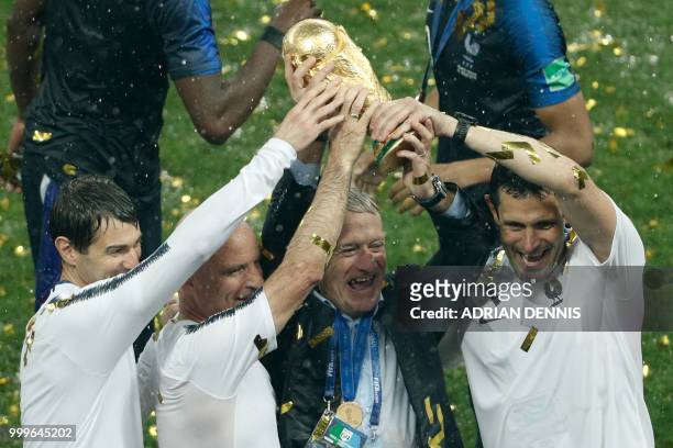 France's coach Didier Deschamps , France's assistant coach Guy Stephan and members of staff hold the trophy as they celebrate during the trophy...