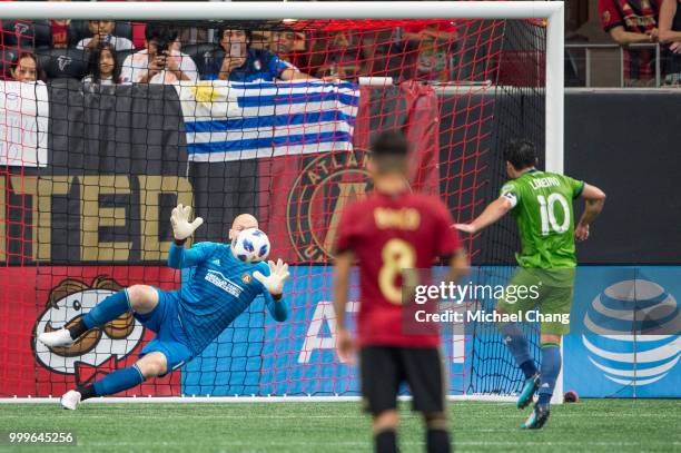 Brad Guzan of Atlanta United attempts to block a shot from Nicolas Lodeiro of Seattle Sounders FC 2 during the game at Mercedes-Benz Stadium on July...