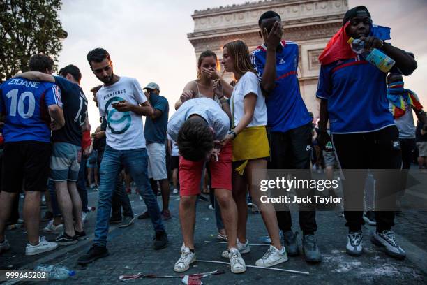 French football fans react to tear gas as they celebrate on the Champs-Elysees after France's victory against Croatia in the World Cup Final on July...