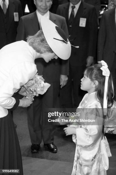 Princess Diana, Princess of Wales receives a flower bouquet from a Japanese girl wearing kimono during her visit to the Honda Motor Co headquarters...