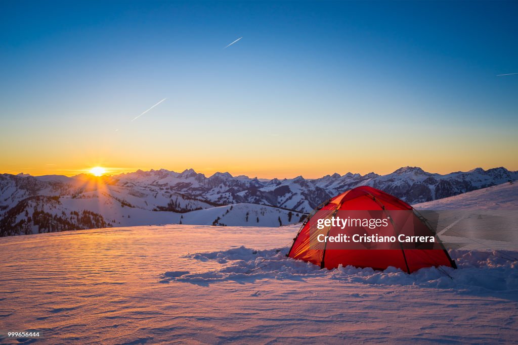 Sunset with tent and snow mountains