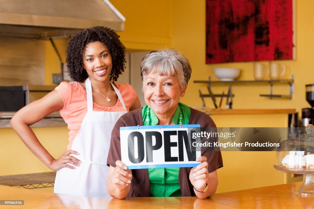 African American business owners in cafe holding open sign