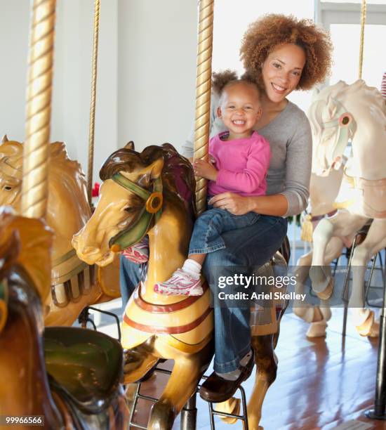 black mother and daughter riding carousel - tierfigur stock-fotos und bilder