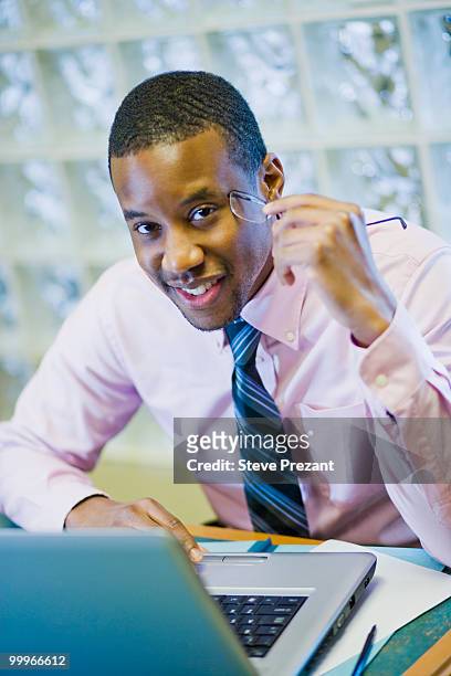 african american businessman sitting at desk - steve prezant stock pictures, royalty-free photos & images