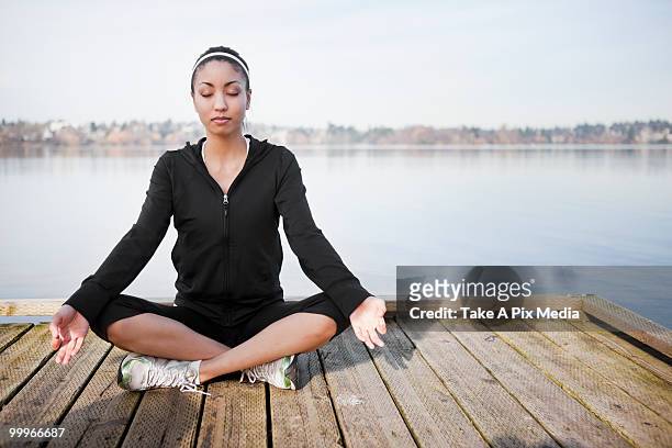mixed race woman practicing yoga on pier - mixed age range stock-fotos und bilder