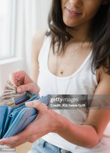 mixed race woman taking money from wallet - jgi jamie grill stock pictures, royalty-free photos & images