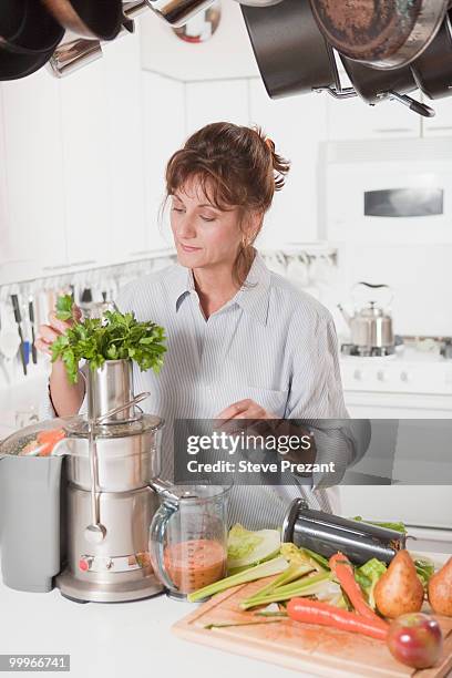 caucasian woman juicing vegetables in kitchen - steve prezant stock pictures, royalty-free photos & images