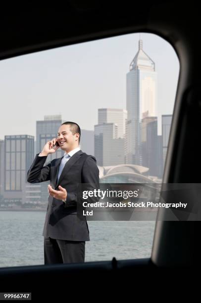 asian businessman talking on cell phone in urban area - fensterfront innen stock-fotos und bilder