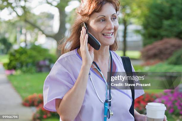 caucasian nurse talking  on cell phone in park - steve prezant stock pictures, royalty-free photos & images