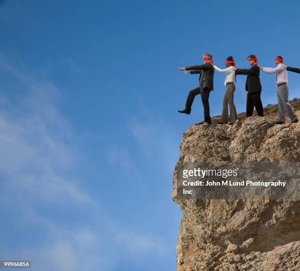 business people in blindfolds walking off cliff - businessman in black suit photos et images de collection