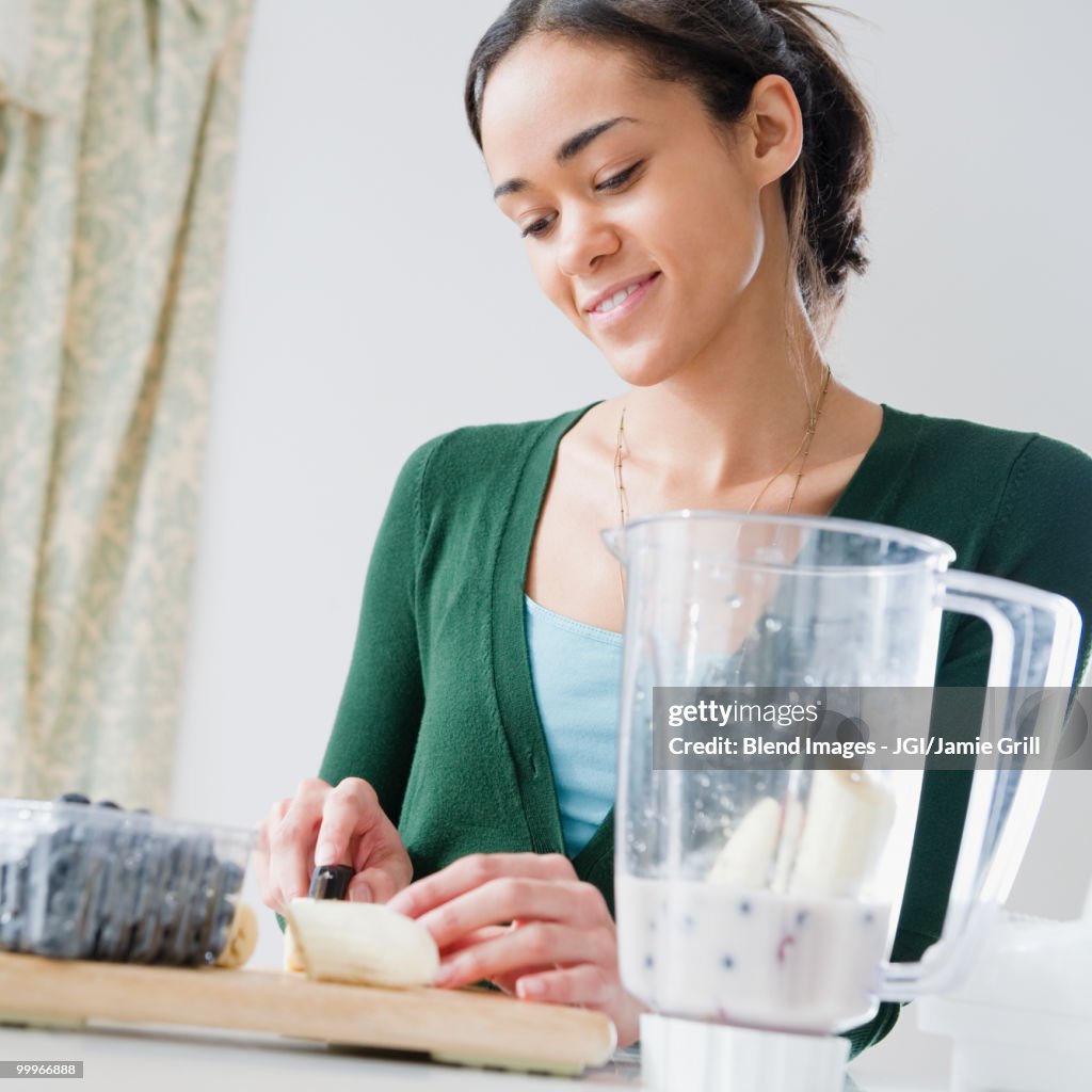 Mixed race woman preparing smoothie
