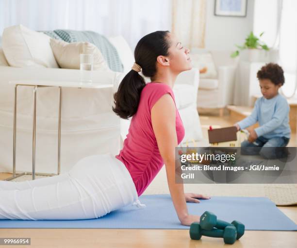 mixed race mother practicing yoga - blend stockfoto's en -beelden