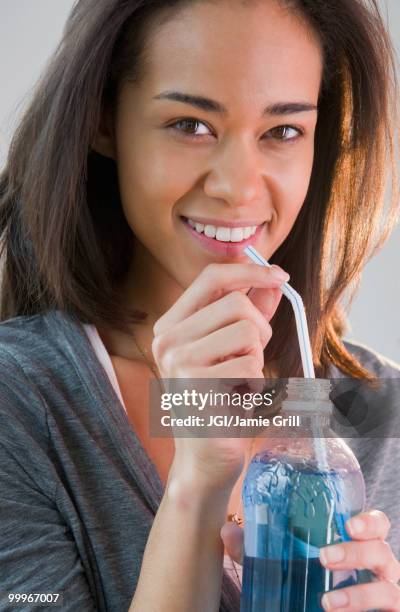 mixed race woman drinking soda through straw - jgi jamie grill stock pictures, royalty-free photos & images