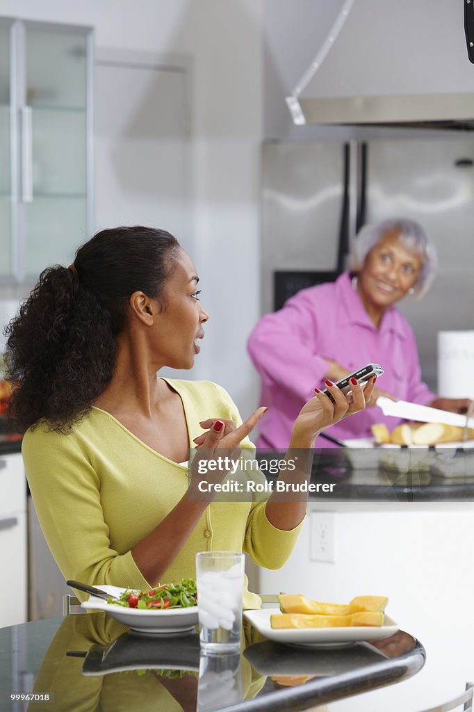 African American woman eating salad and talking on cell phone