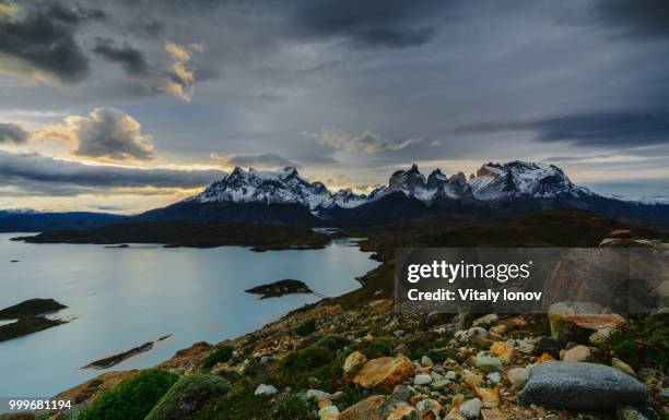 a view of the mountains and the lake during a sunset in the torres del paine national park.... - torres stock pictures, royalty-free photos & images