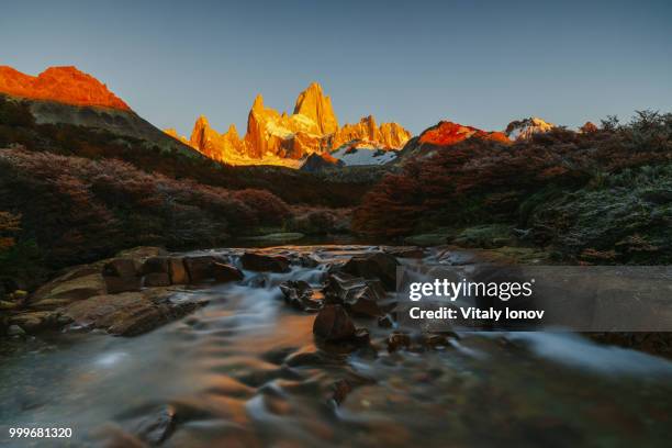 view of mount fitz roy and the river in the national park of los glaciares during sunrise. autumn... - fitz roy stock-fotos und bilder