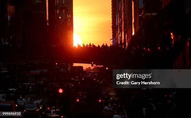 The setting sun moves across 42nd Street as people stand on the Pershing Square Bridge on Park Avenue during Manhattanhenge on July 13, 2018 in New...