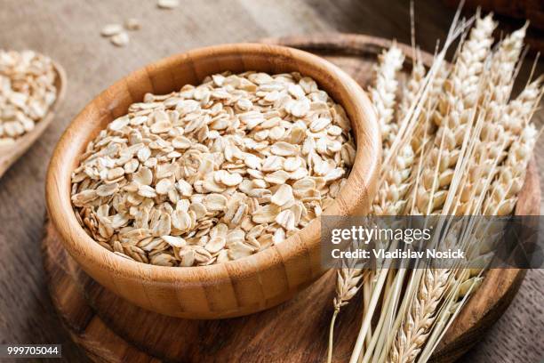 rolled oats or oat flakes and golden wheat ears on wooden background. - makrobiotik stock-fotos und bilder
