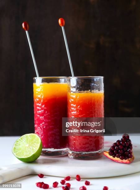 cocktail tequila sunrise on white table . pomegranate seeds and - tequila sunrise stock pictures, royalty-free photos & images